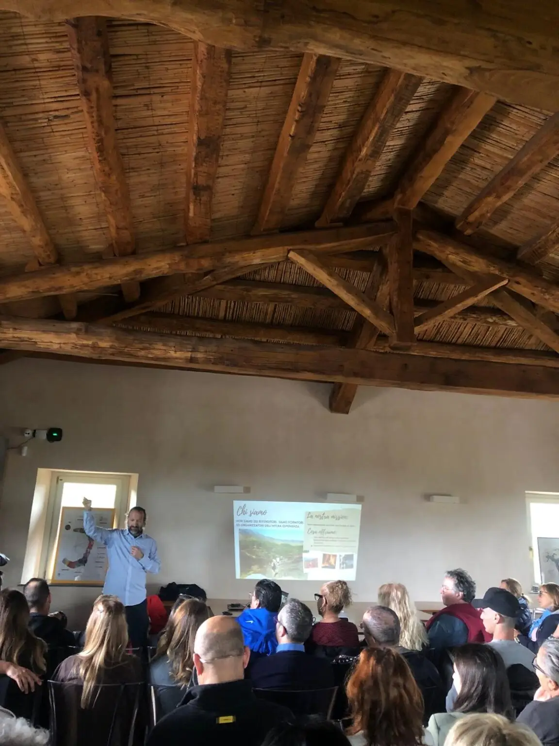 Speaker presenting to guests during an exclusive luxury business meeting in a Sicilian countryside venue.