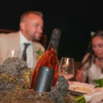 Bottiglia di vino rosé usata come centrotavola su un tavolo di matrimonio di lusso durante un’elegante celebrazione in Sicilia.