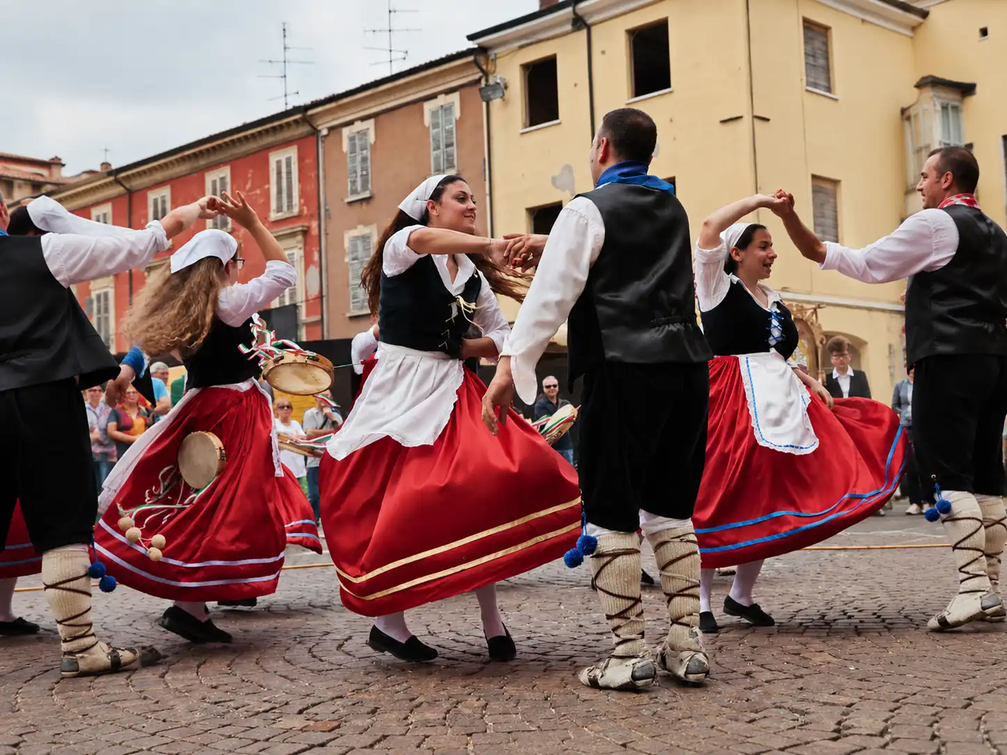 Performers in traditional Sicilian costumes dancing during a lively cultural festival and folk dance experience in Sicily.